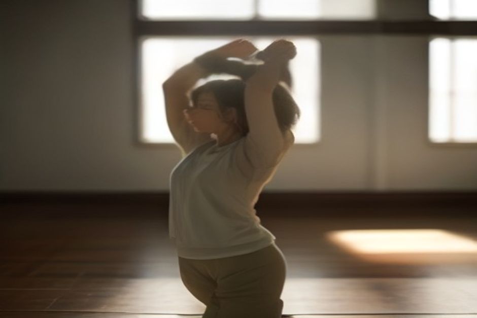 A practitioner mid sun salutation in a bright studio, arms raised overhead in the first movement of the sequence