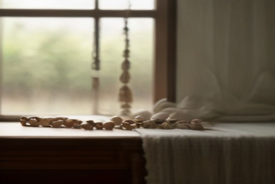 Wooden mala beads with a simple tassel resting on linen cloth in warm window light