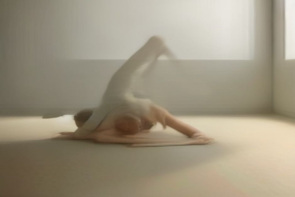 A practitioner holding eight-angle pose, body extended sideways between bent arms, on a mat in a calm studio