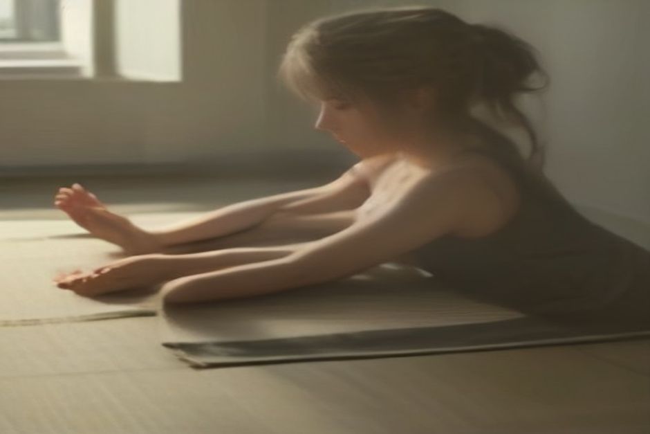 A person in thread the needle pose on a mat, one arm threaded under the body, temple resting down, soft calm light