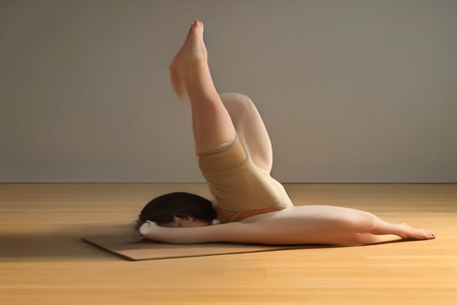 Person in triangle pose with the lower hand resting on a block, top arm reaching up, warm studio light