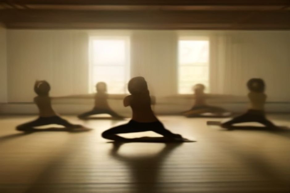 A row of practitioners moving through sun salutations at dawn in a quiet Mysore-style practice room