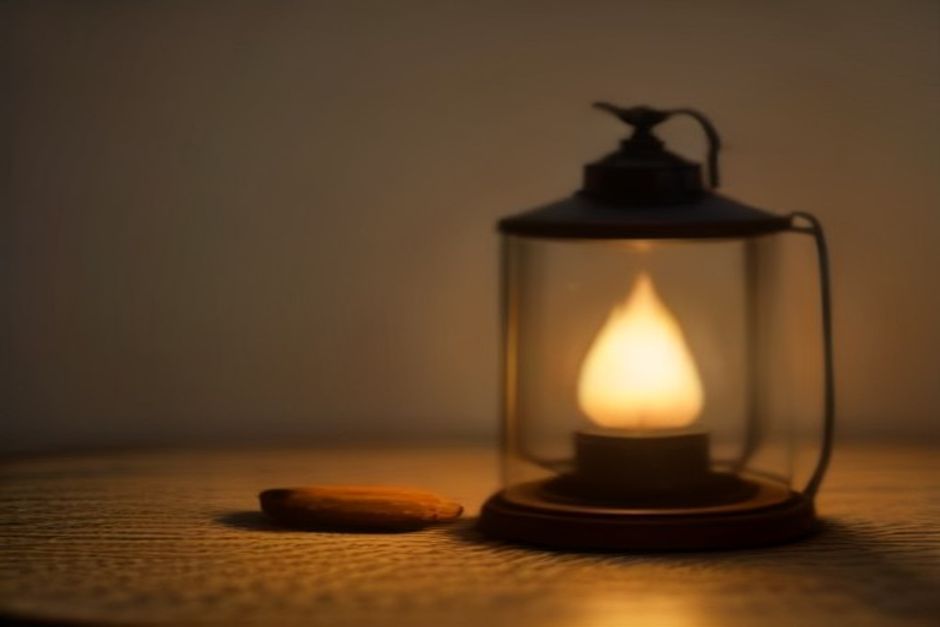 A single lit oil lamp on a wooden table in a dim, calm room, warm earthy tones, minimalist